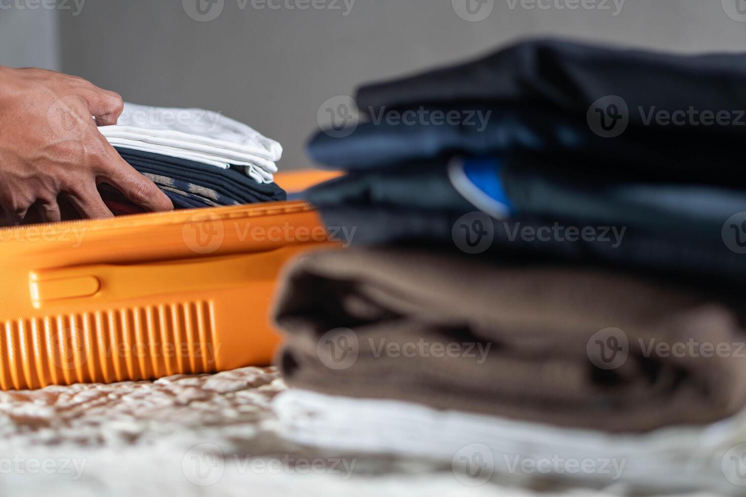 Packing clothes into an orange suitcase photo