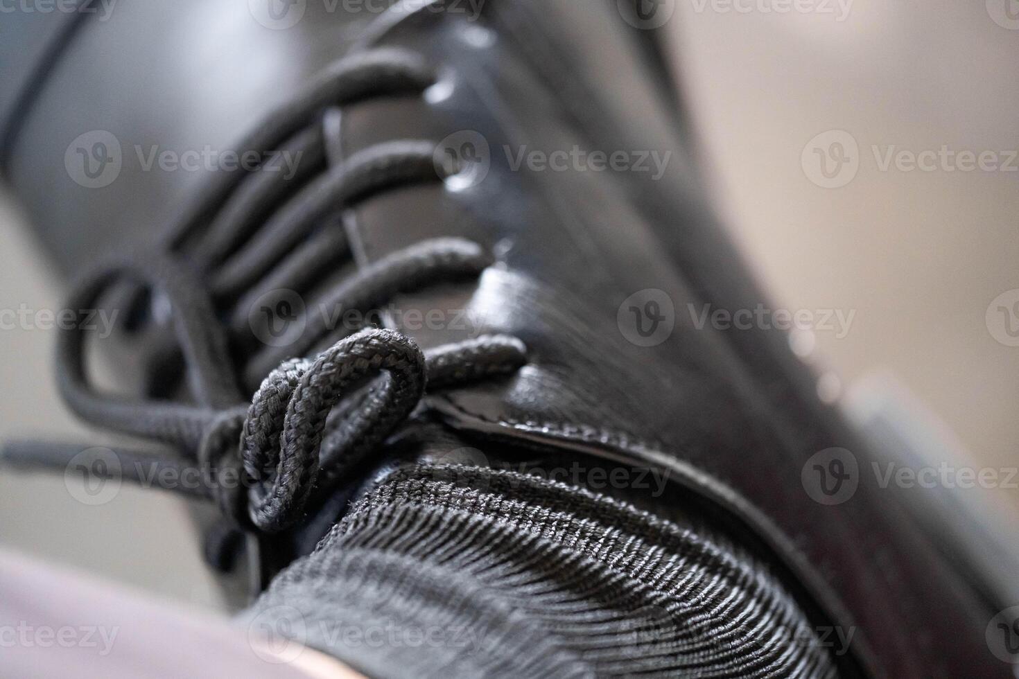 Close-up of black leather boot with laces and gray sock photo
