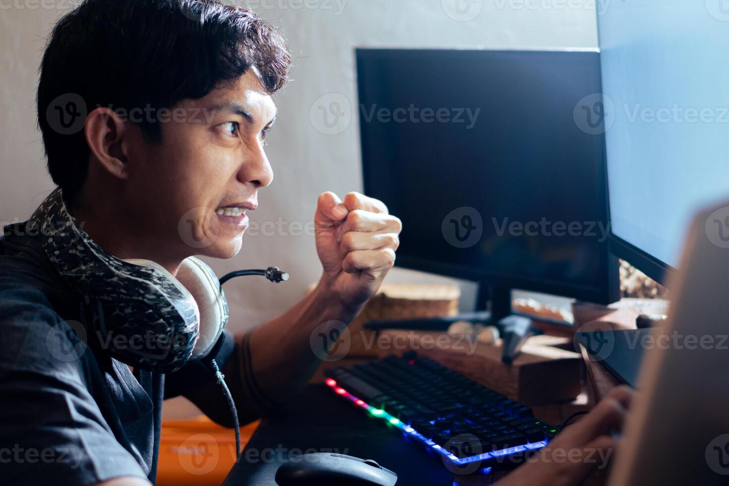 Frustrated gamer clenching fist at computer screen photo