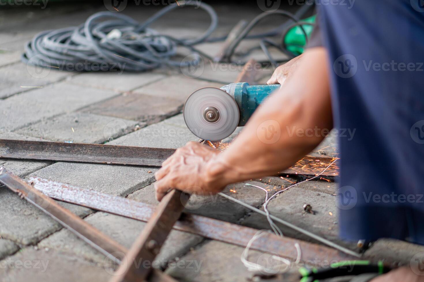 Person using angle grinder to cut metal bars photo