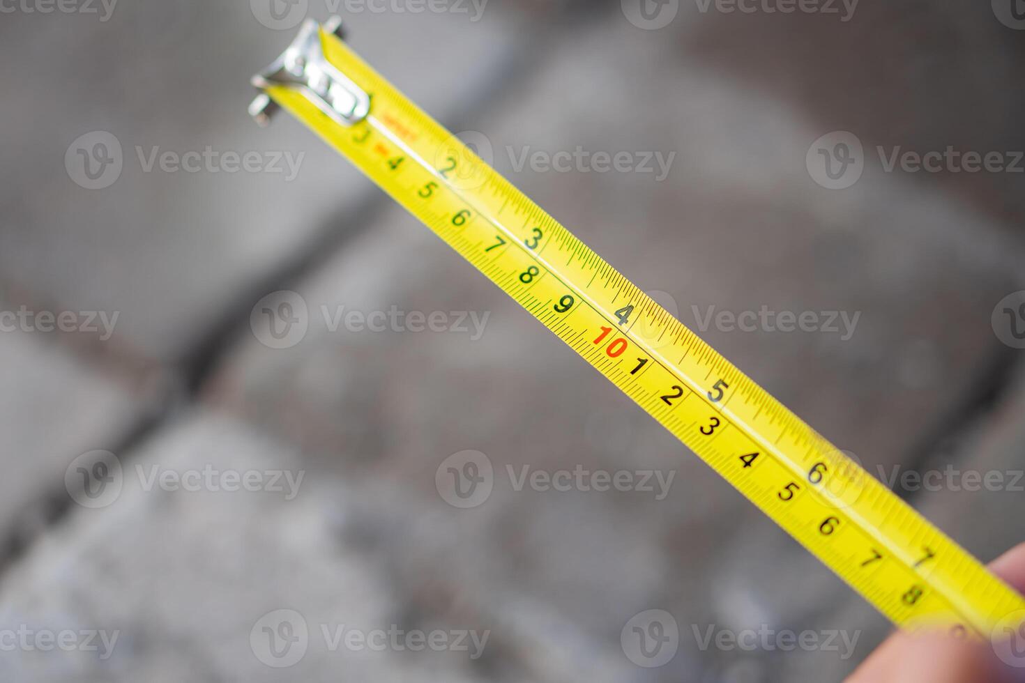 Yellow measuring tape extended over gray bricks photo