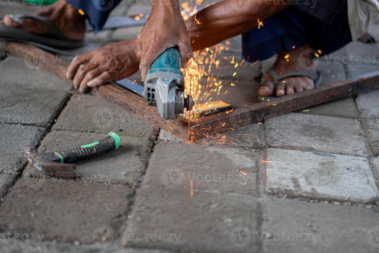 Worker using angle grinder to cut metal photo