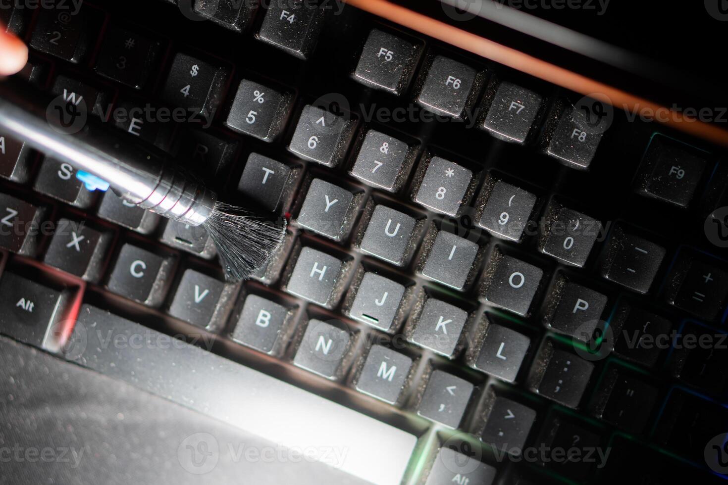 Cleaning a dusty computer keyboard with a brush photo