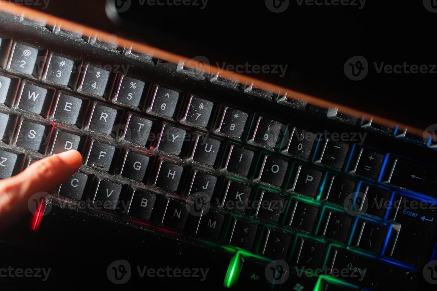 Finger pressing ID key on dusty backlit keyboard photo