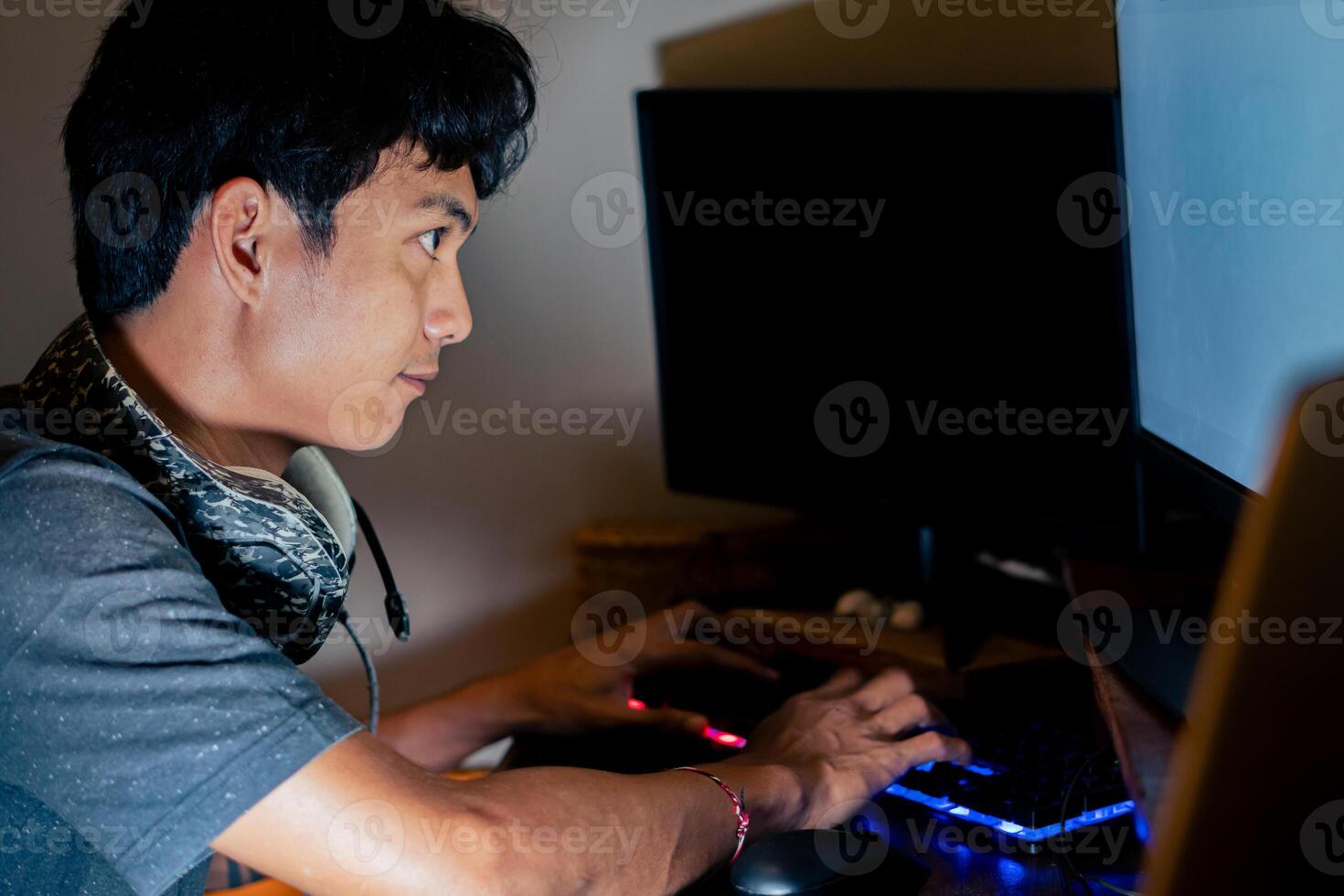 Young man typing on computer in dimly lit room photo