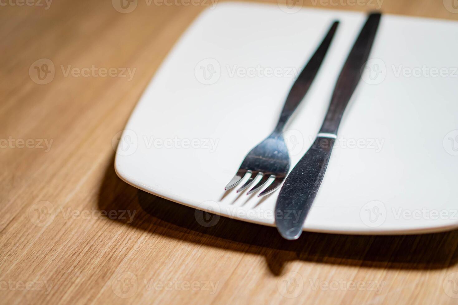 Hand placing stacked plates with cutlery on table photo