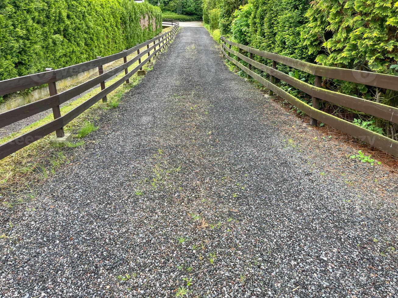 Made of gravel road and bordered by a fence for the driveway to the houseMade of gravel road and bordered by a fence for the driveway to the house photo