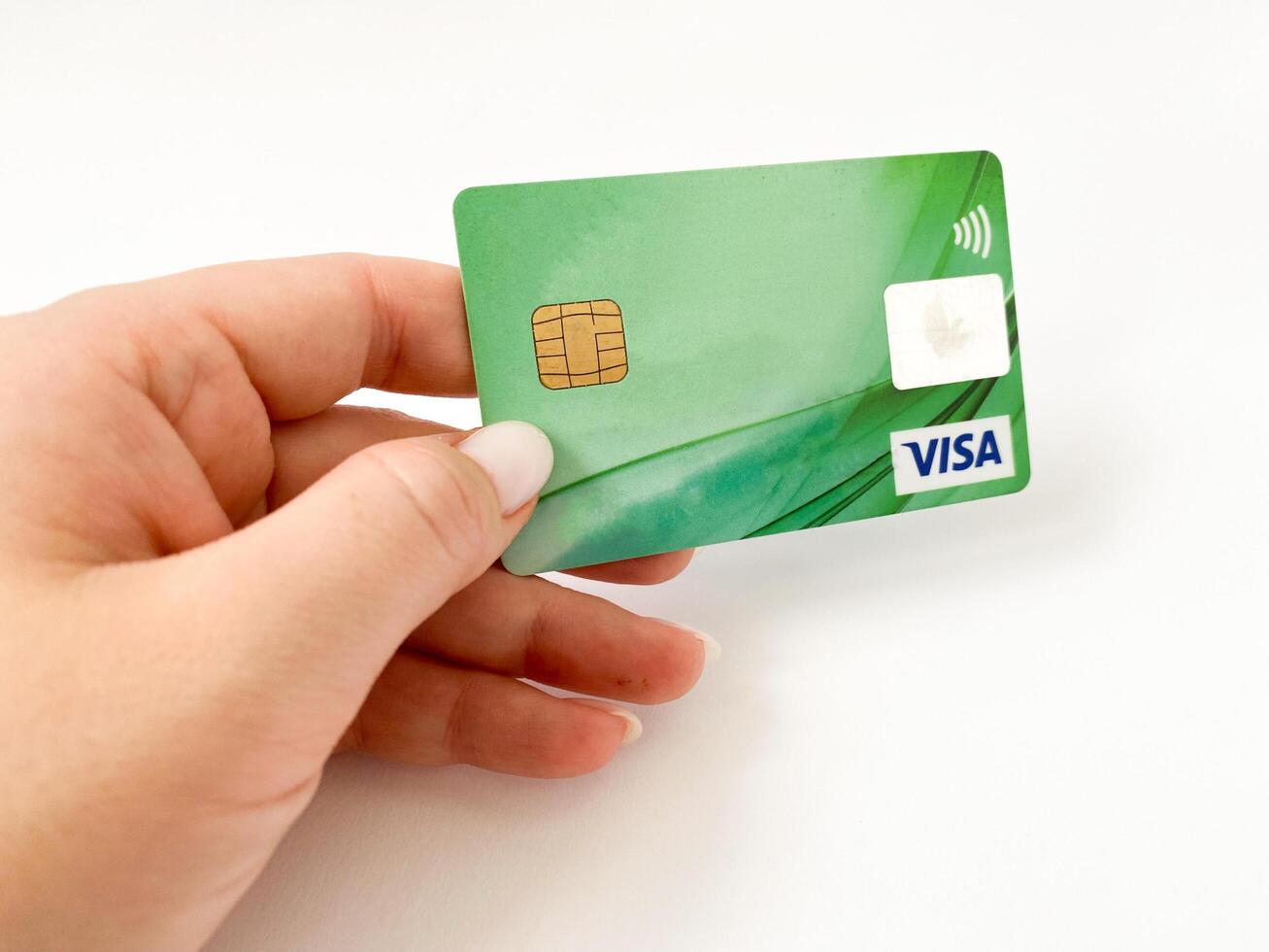 Bialystok, Poland - 08.07.2021 Visa bank card in hand on a white isolated background. Non-cash payments with a Visa card. Online card payments photo