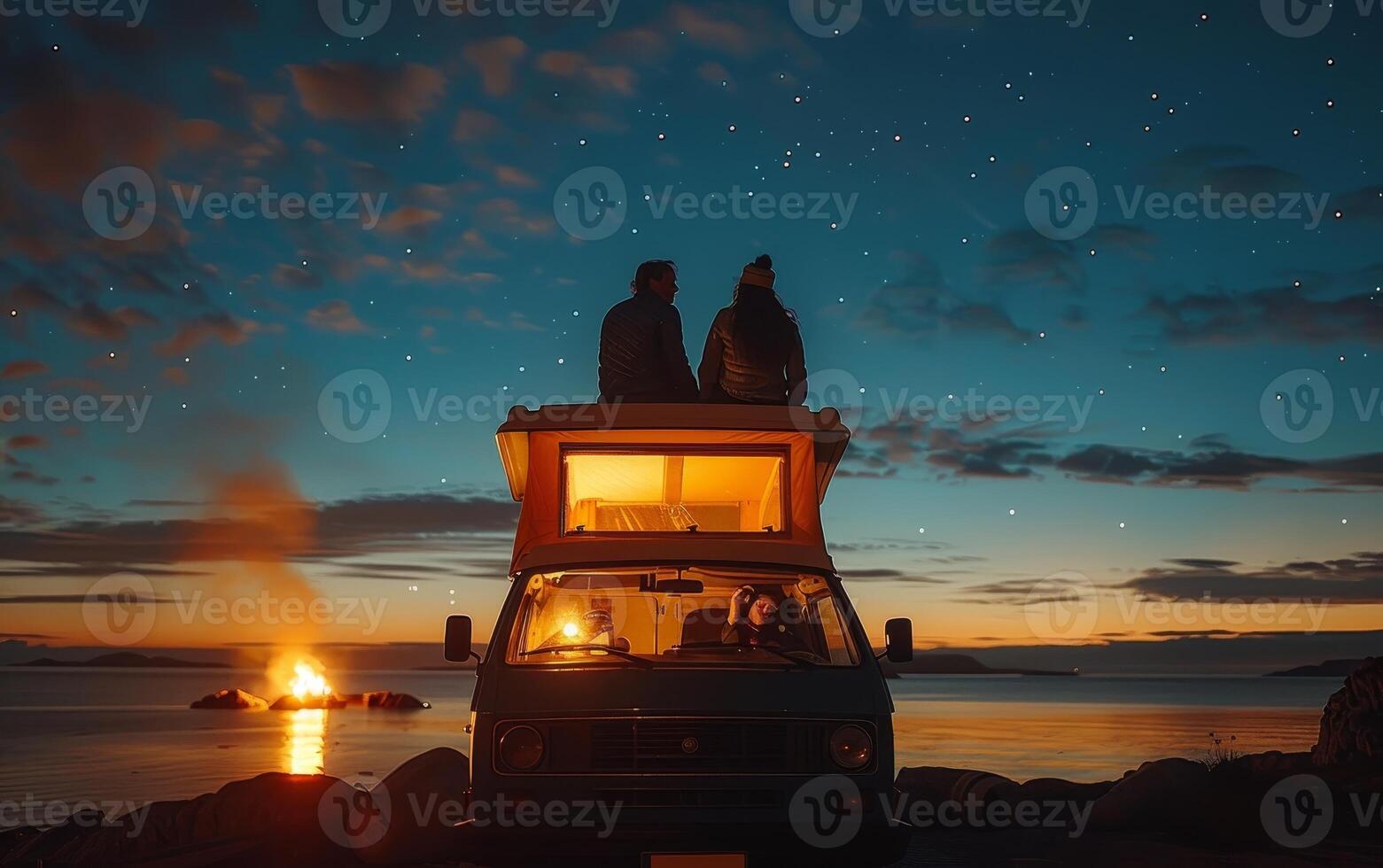 Couple Sitting on Top of Camper Van at Sunset photo