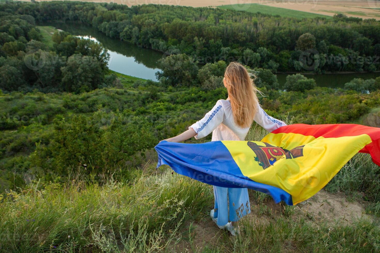 The beautiful lady holding the flag of the Republic of Moldova on a beautiful hill in nature. photo