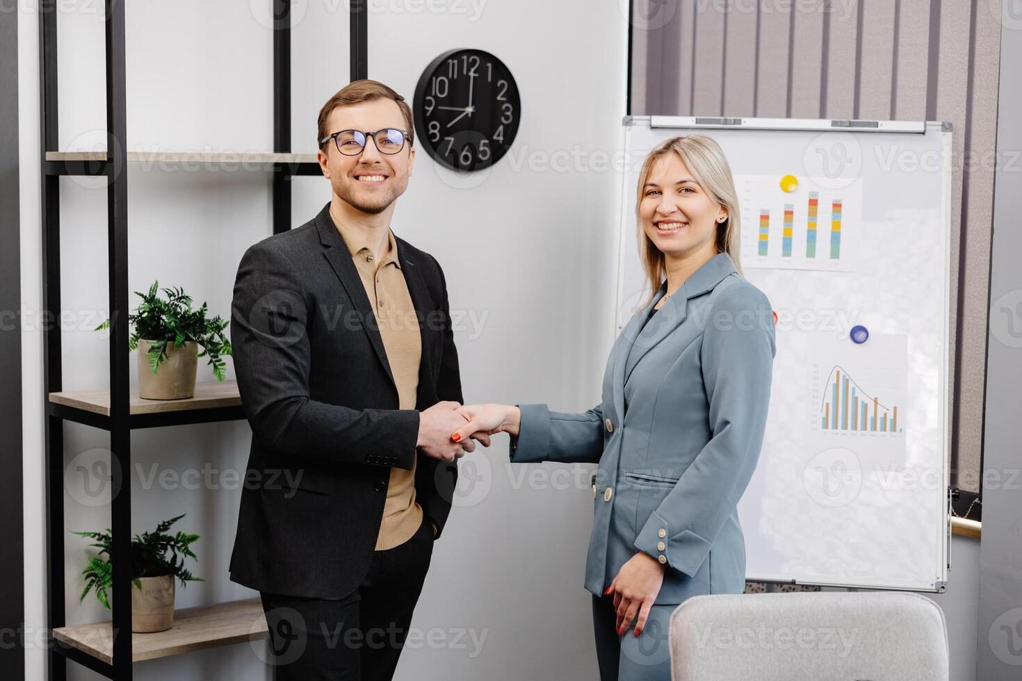 Smiling young female employee shake hand of male colleague make agreement or close deal at office meeting. Happy diverse business partners handshake get acquainted greeting at briefing. photo