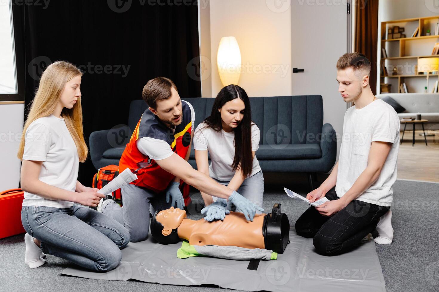 Group of people learning how to make first aid heart compressions with dummies during the training indoors photo