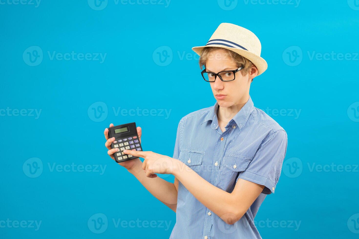 Surprised student holding calculator. Portrait of funny cute teen boy holding calculator in his hand. Shocked child with calculator looking at camera. photo