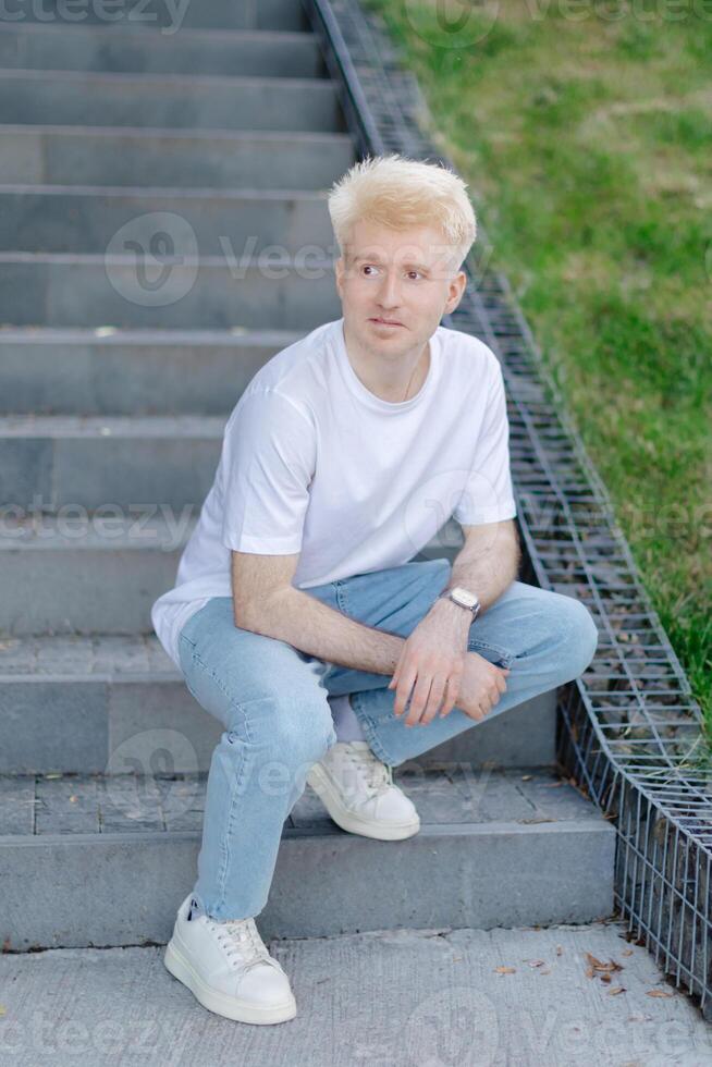 Young man standing outdoors in the street in summer time photo