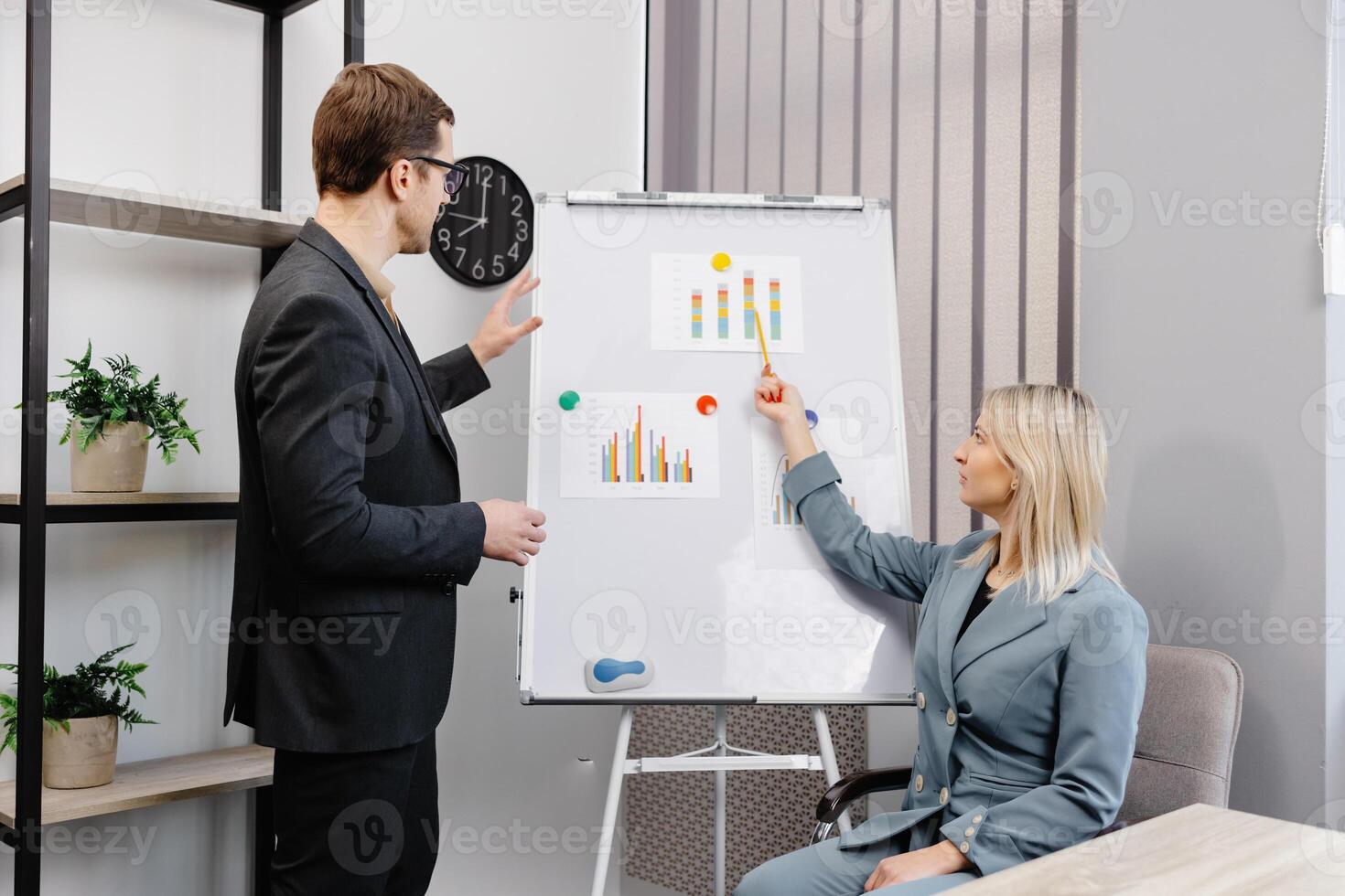 Confident business coach gives presentation on flip chart. A young woman and a man are talking and discussing business project schedules in the office photo