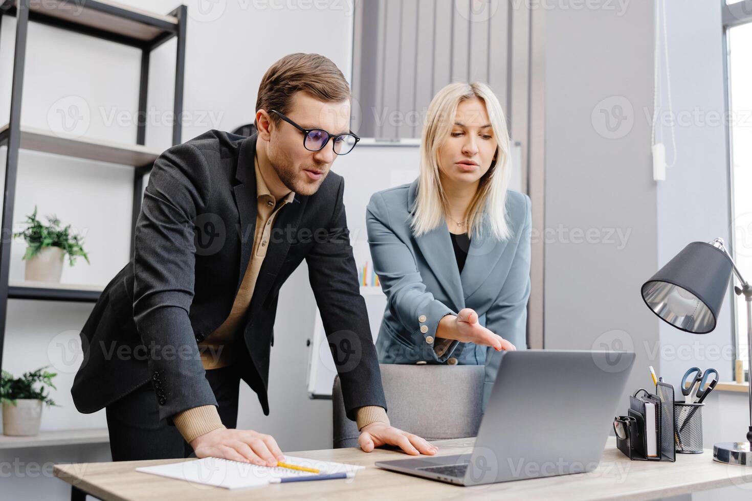 Concentrated male businessman looking at computer monitor, working with a young female worker on a project, people holding a meeting with a client or interviewing a job candidate. photo