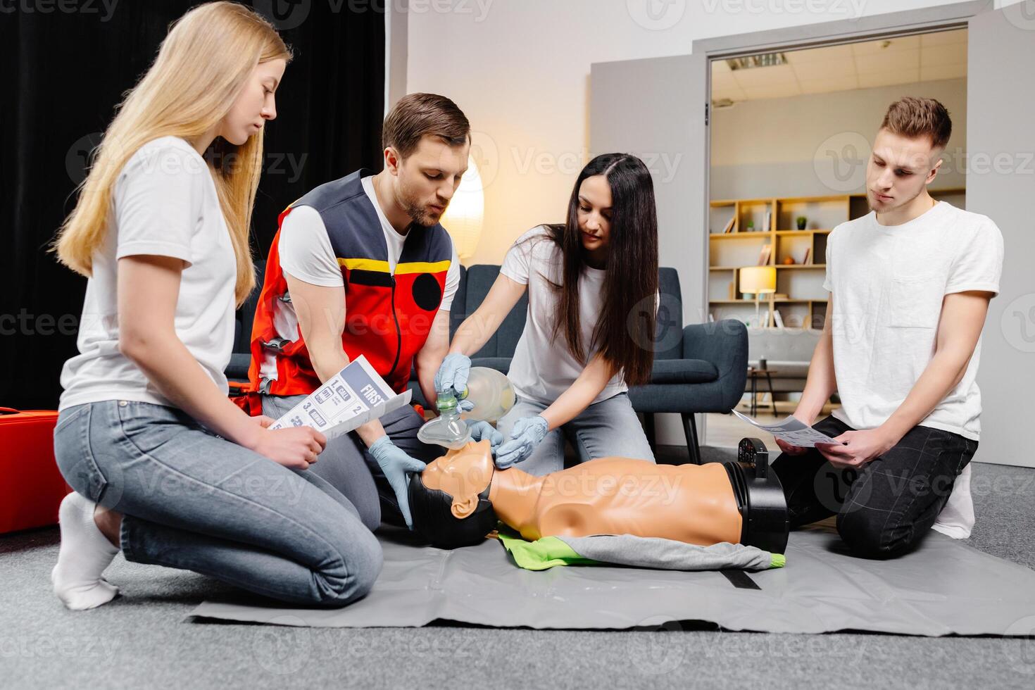 Group of people learning how to make first aid heart compressions with dummies during the training indoors photo