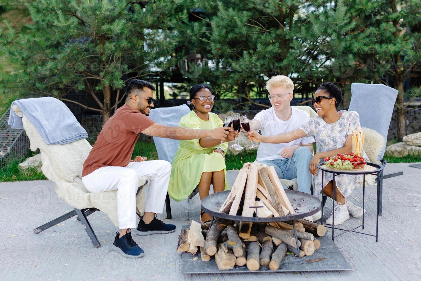 Friends celebrating outside, drinking wine and eating fruit on a picnic photo