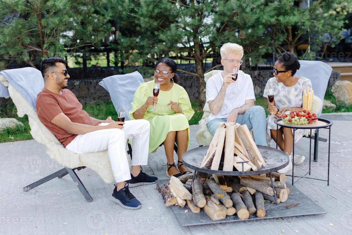 Friends celebrating outside, drinking wine and eating fruit on a picnic photo