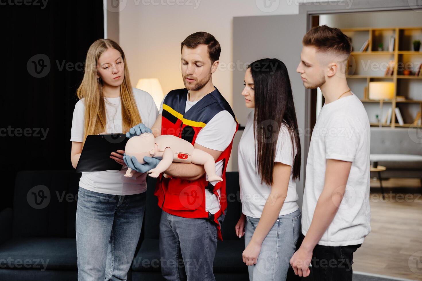 Group of people learning how to make first aid with dummy child during the training indoors photo