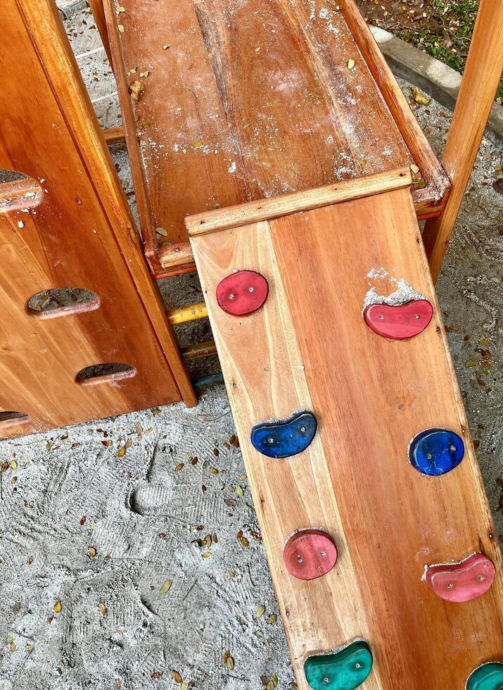 Wooden climbing wall toy in outdoor park playground isolated on vertical sand ground flooring background from top angle view. photo