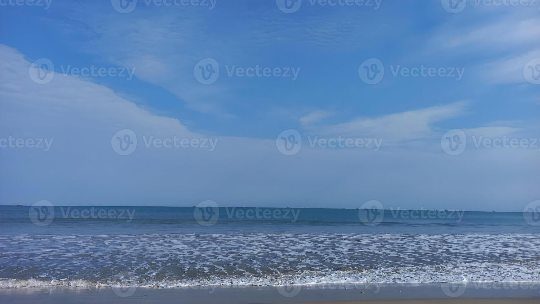 a beach with a blue sky and white clouds photo