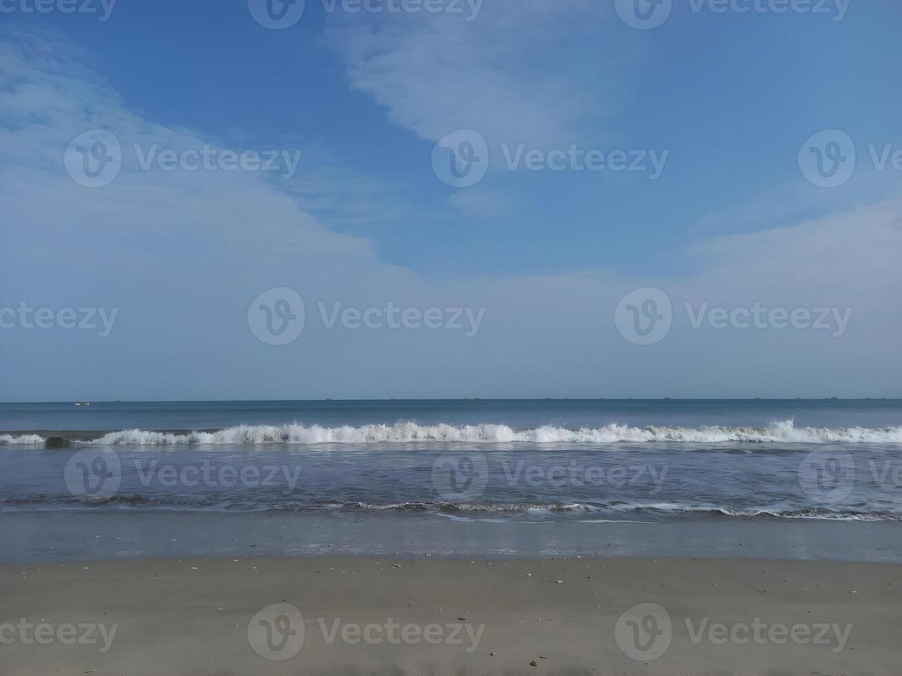 a beach with waves and a blue sky photo