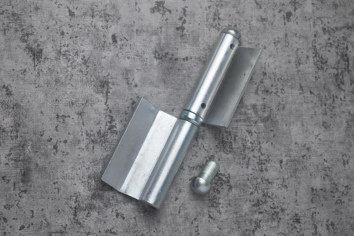 Photo from above of a fireproof iron hinge with a cement background