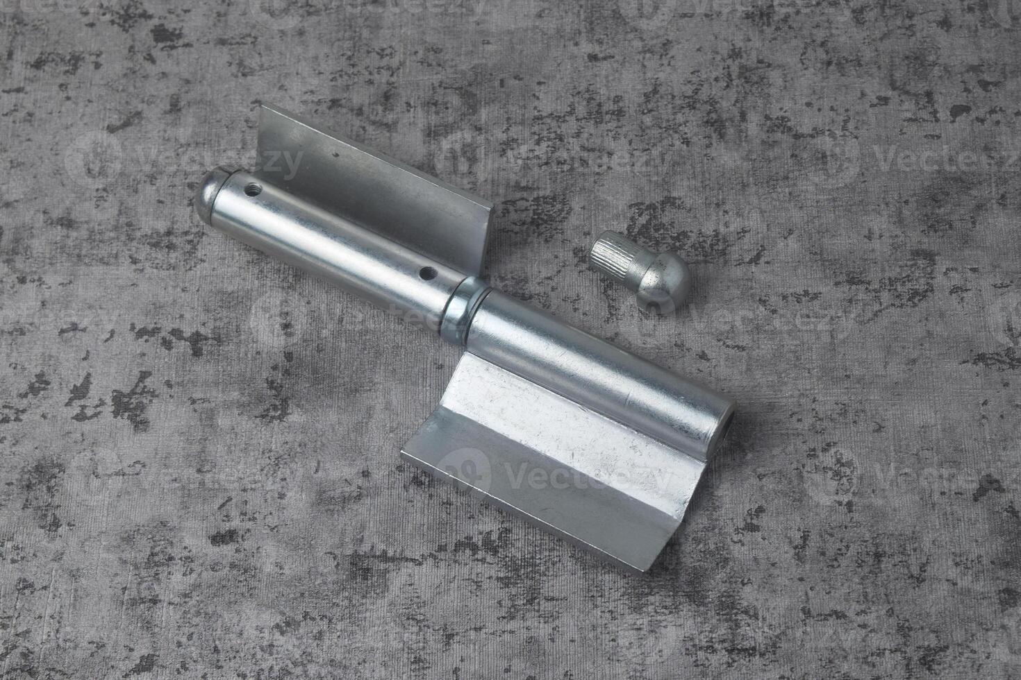 Photo from above of a fireproof iron hinge with a cement background