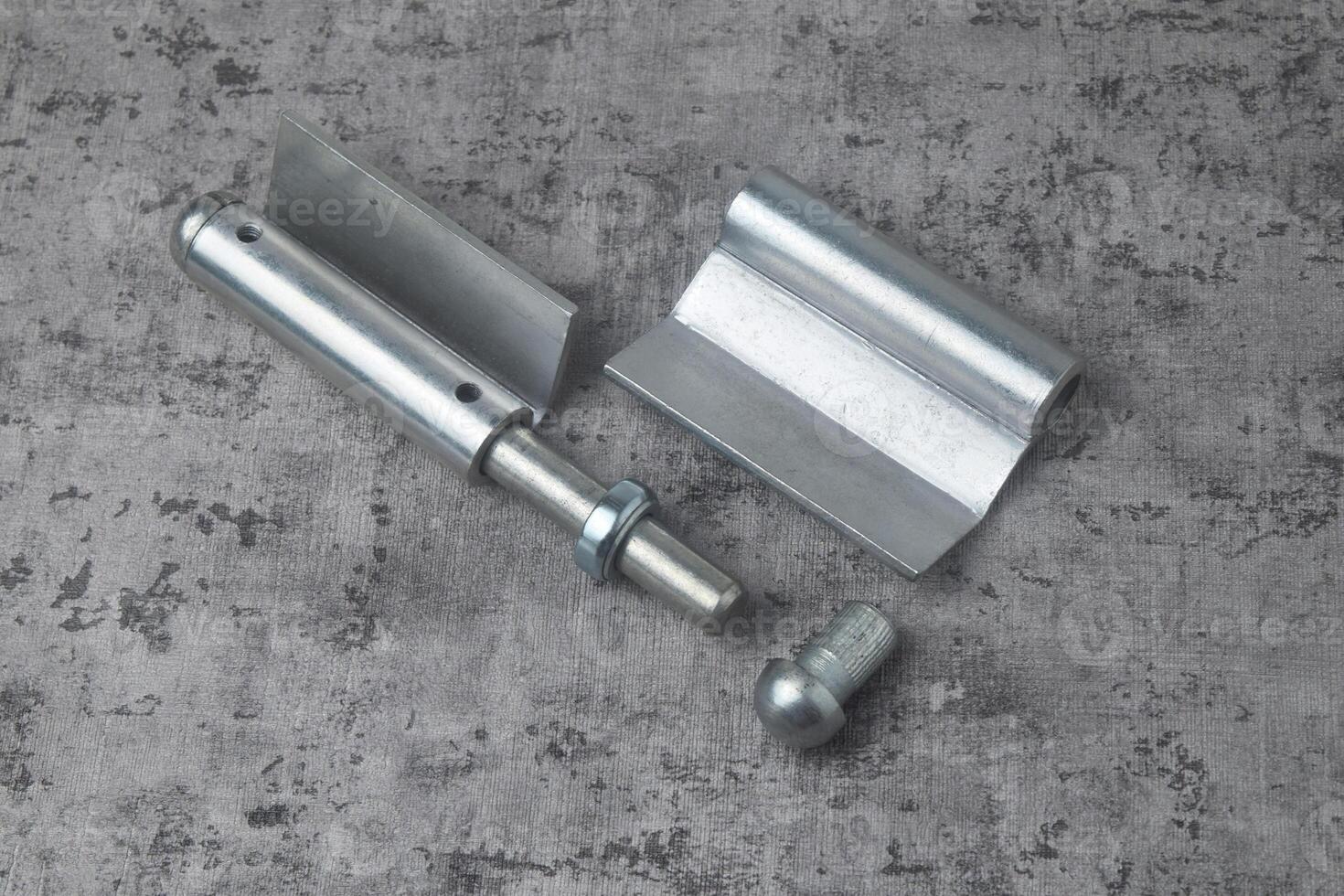 Photo from above of a fireproof iron hinge with a cement background