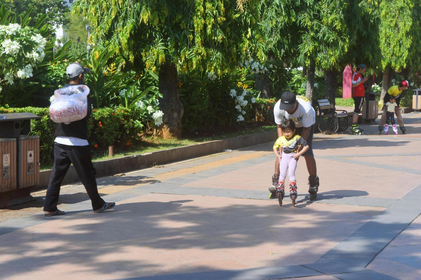 Semarang, Indonesia, 2023 - A girl is learning to use roller skates with a male coach at Semarang city photo
