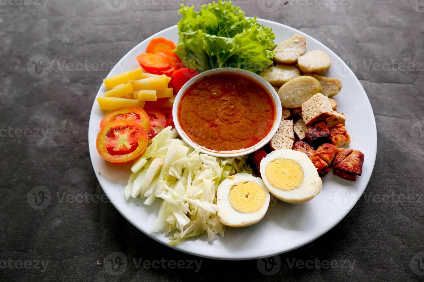 Gado-gado is a traditional Indonesian salad consisting of vegetables, potatoes, tempeh, tofu, carrots, tomatoes, lettuce, eggs and peanut sauce. Salad photo