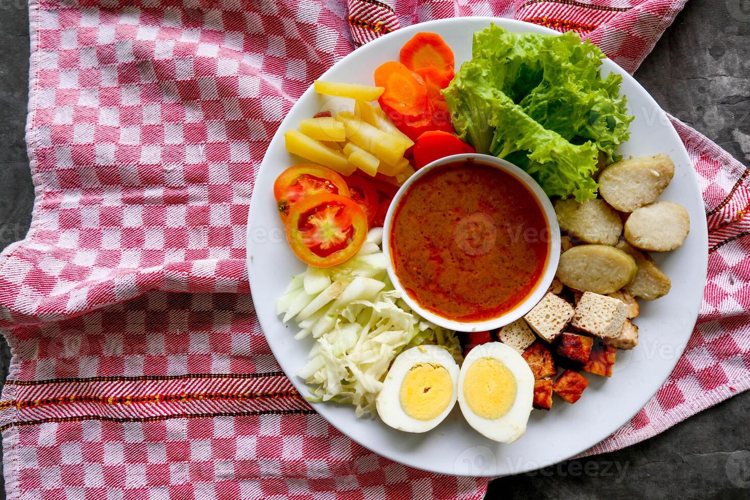 Gado-gado is a traditional Indonesian salad consisting of vegetables, potatoes, tempeh, tofu, carrots, tomatoes, lettuce, eggs and peanut sauce. Salad photo
