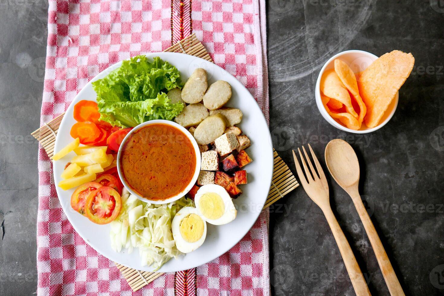 Gado-gado is a traditional Indonesian salad consisting of vegetables, potatoes, tempeh, tofu, carrots, tomatoes, lettuce, eggs and peanut sauce. Salad photo