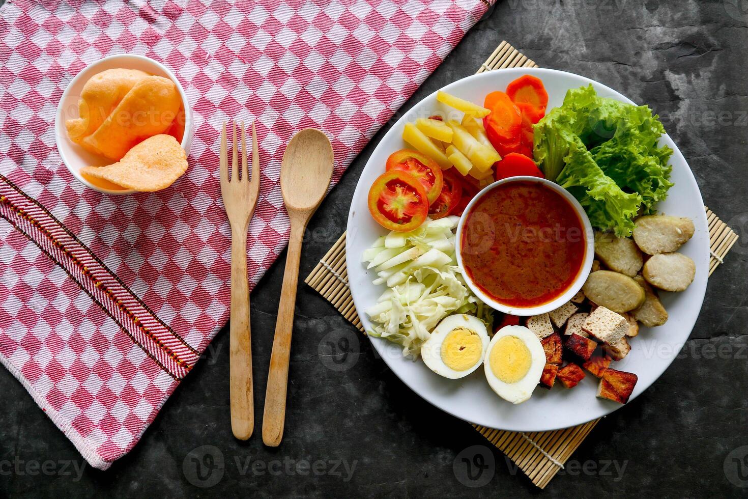 Gado-gado is a traditional Indonesian salad consisting of vegetables, potatoes, tempeh, tofu, carrots, tomatoes, lettuce, eggs and peanut sauce. Salad photo