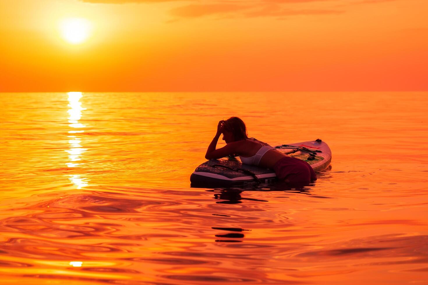 June 26, 2021. Dalaman, Turkey. Woman relax on stand up paddle board at quiet ocean with sunset or sunrise. Woman on Red Paddle SUP board and sunset. photo