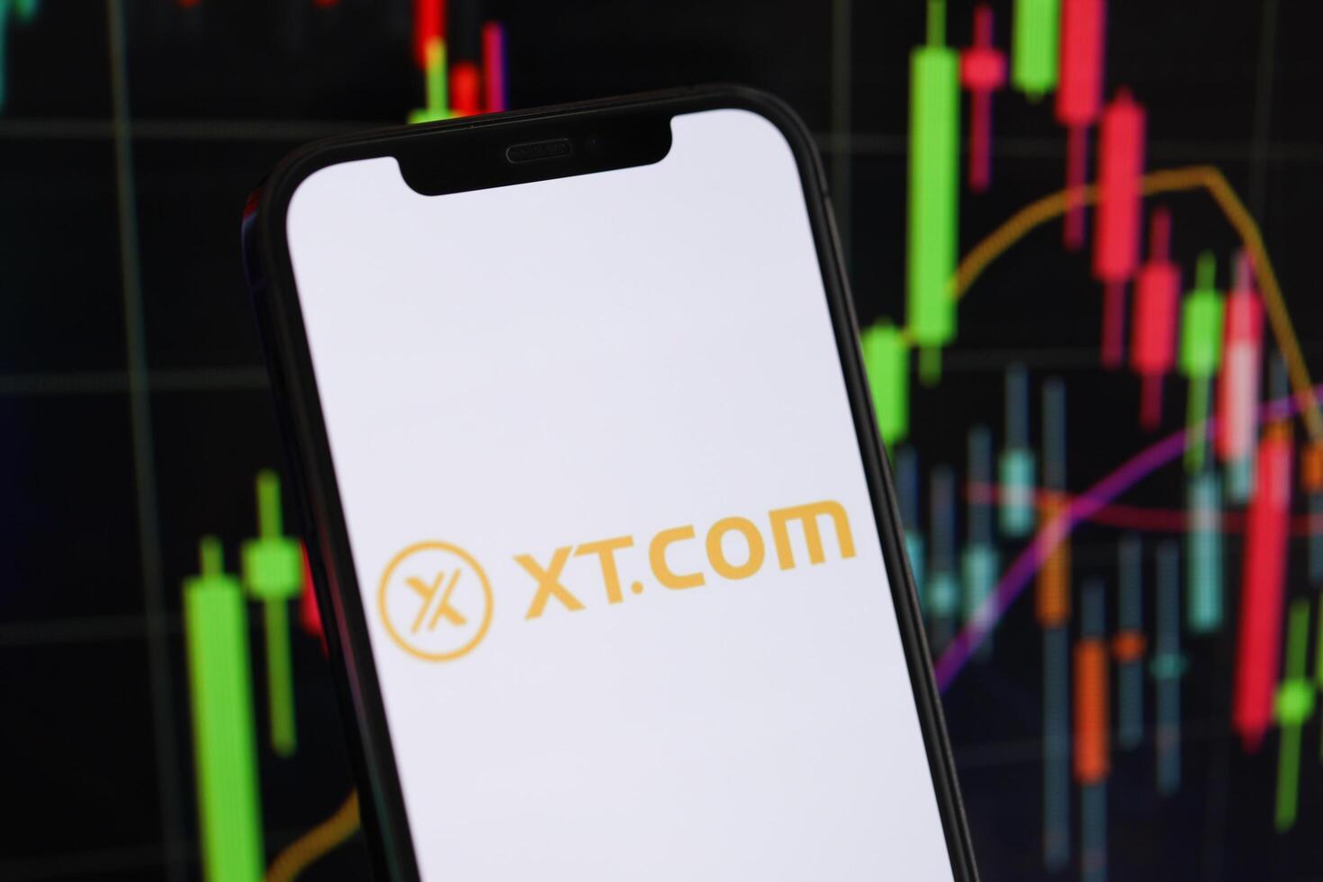 KYIV, UKRAINE - MARCH 15, 2024 XTcom logo on iPhone display screen and crypto currency value charts photo