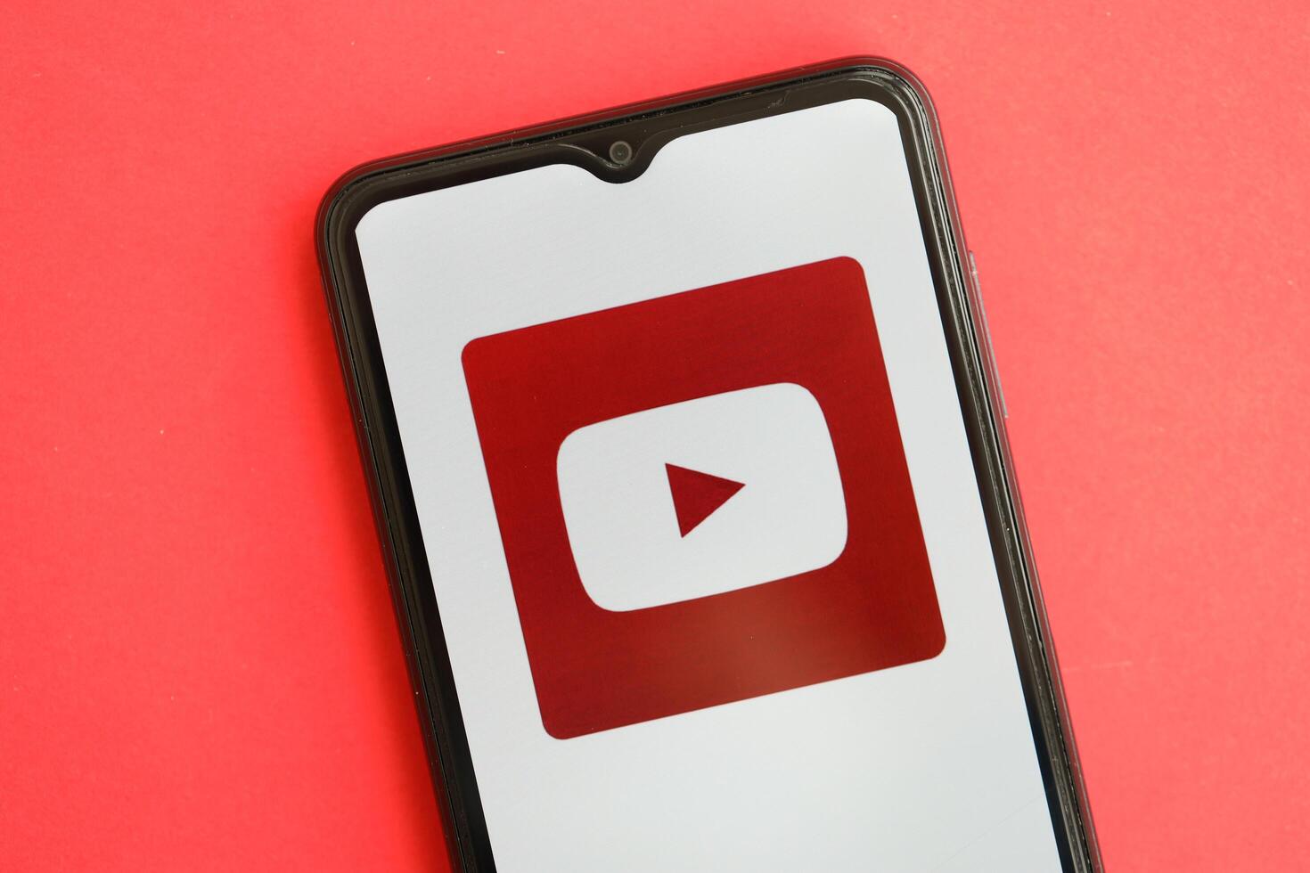 KYIV, UKRAINE - APRIL 1, 2024 Youtube icon on smartphone screen on red table photo