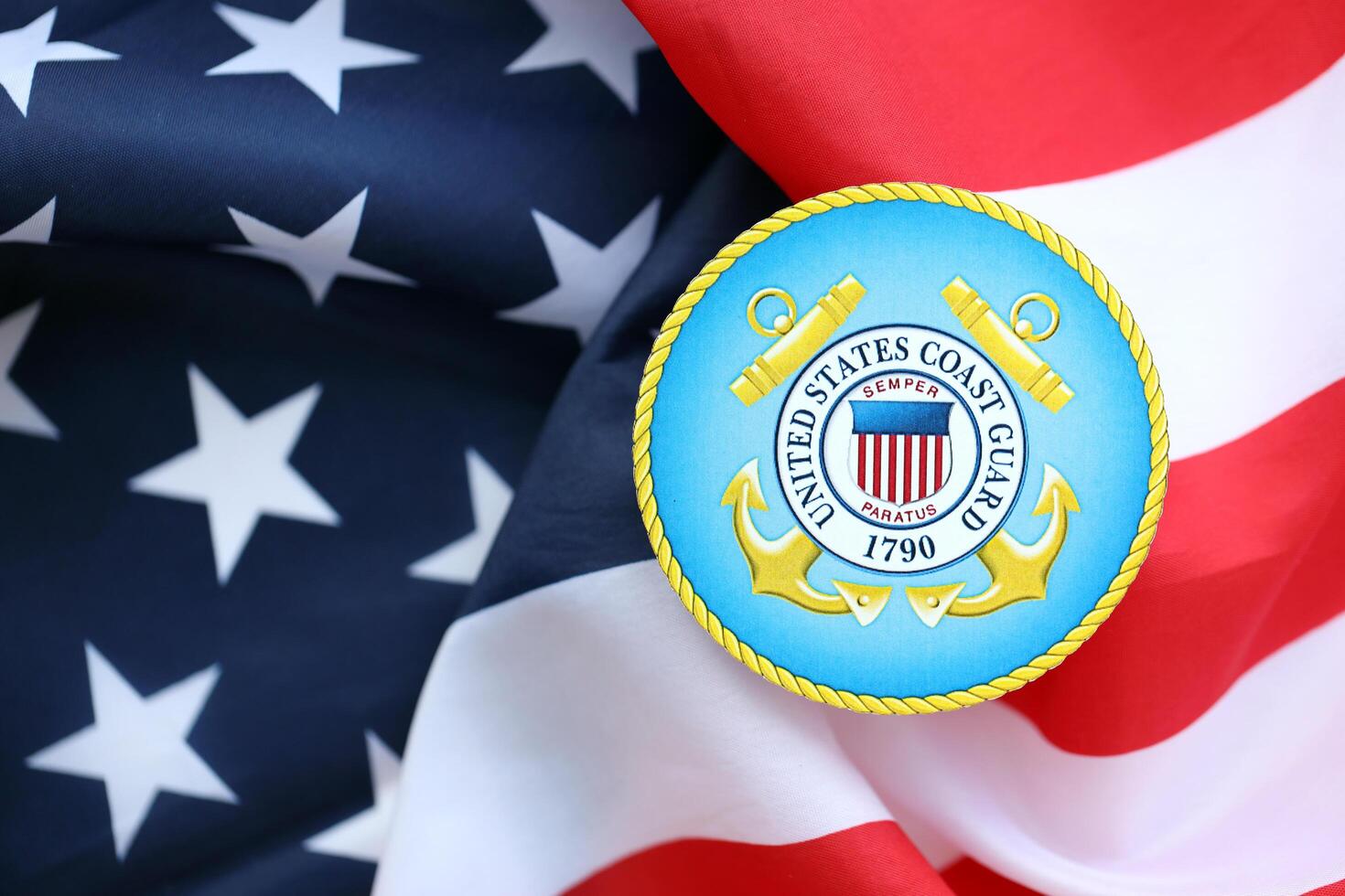 KYIV, UKRAINE - JUNE 26, 2024 United States Coast Guard coat of arms sticker on folded US flag photo