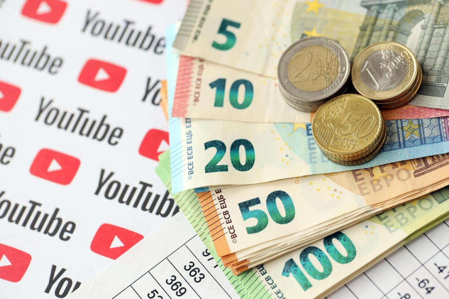 KYIV, UKRAINE - APRIL 20, 2024 YouTube logo and many euro money bills. Symbol of famous social network platform and european currency banknotes photo