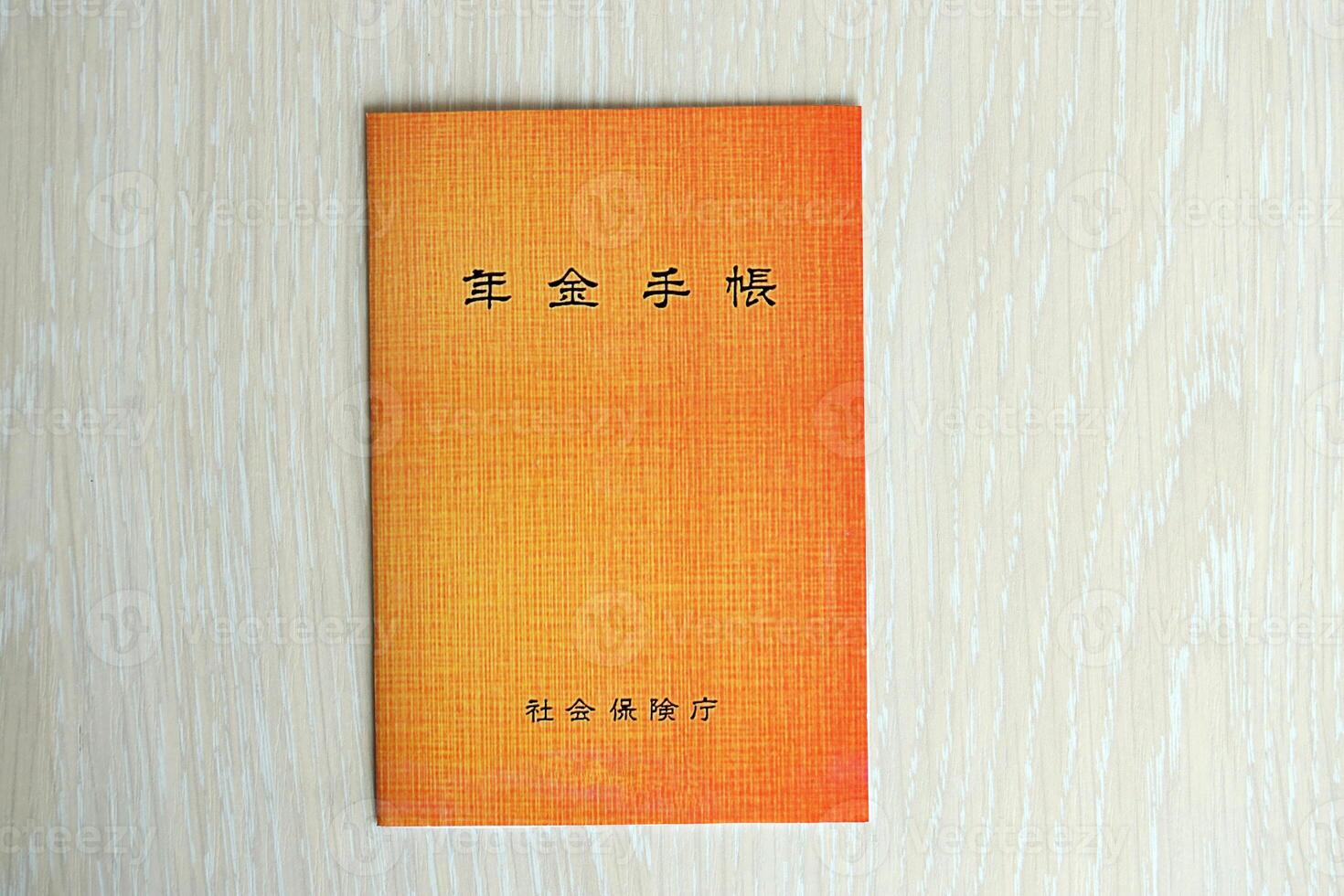 Japanese pension insurance booklet on table. Orange pension book for japan pensioners photo
