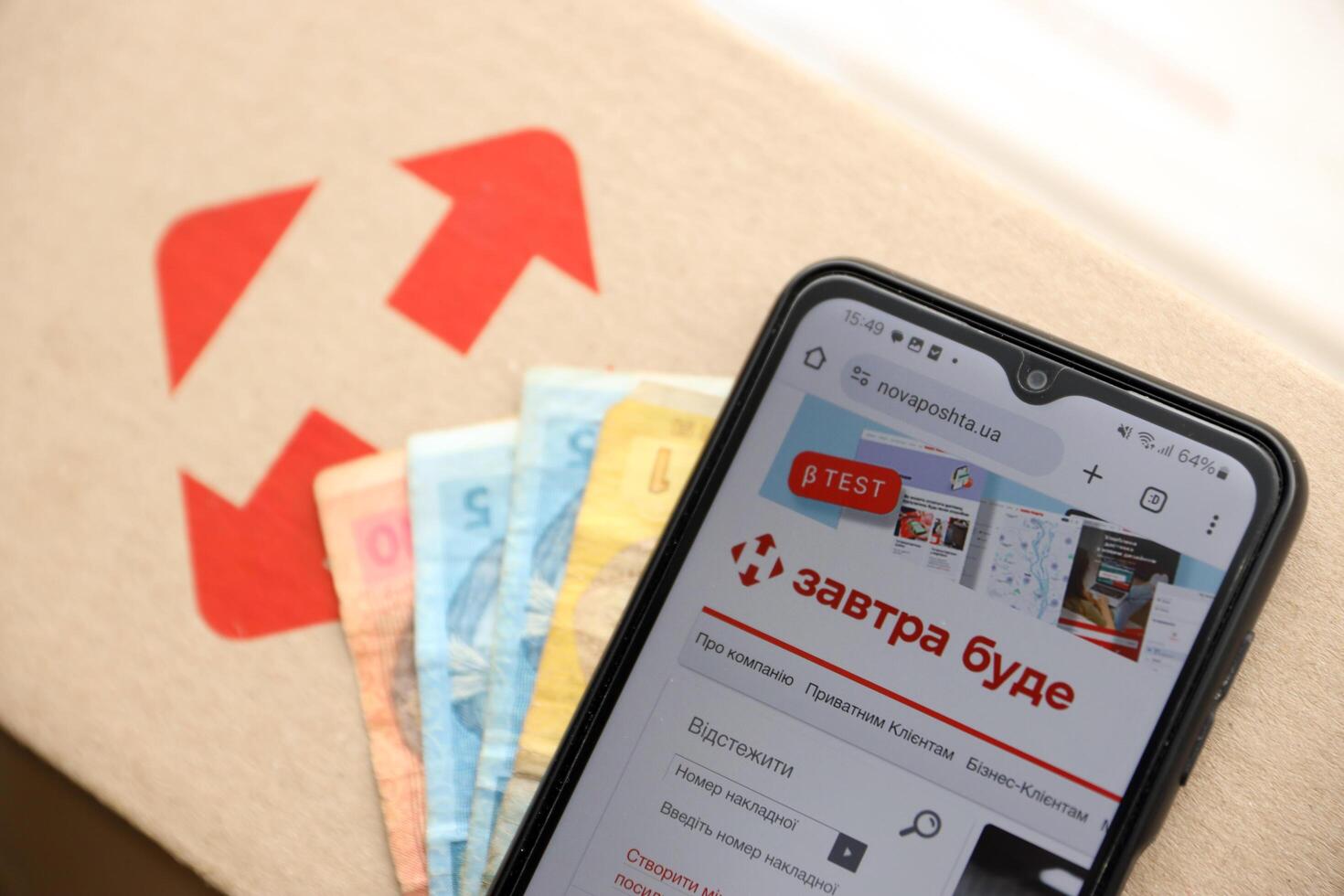 KYIV, UKRAINE - APRIL 20, 2024 Nova Poshta Logotype on cardboard box and website on smartphone screen. Nova Poshta is best ukrainian postal service company photo