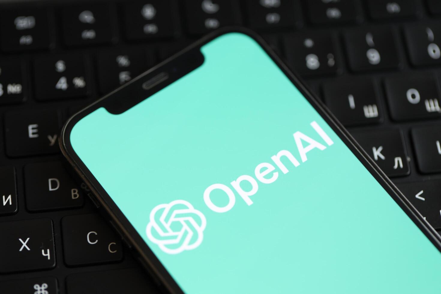 KYIV, UKRAINE - MARCH 17, 2024 OpenAI logo on iPhone display screen and MacBook keyboard photo