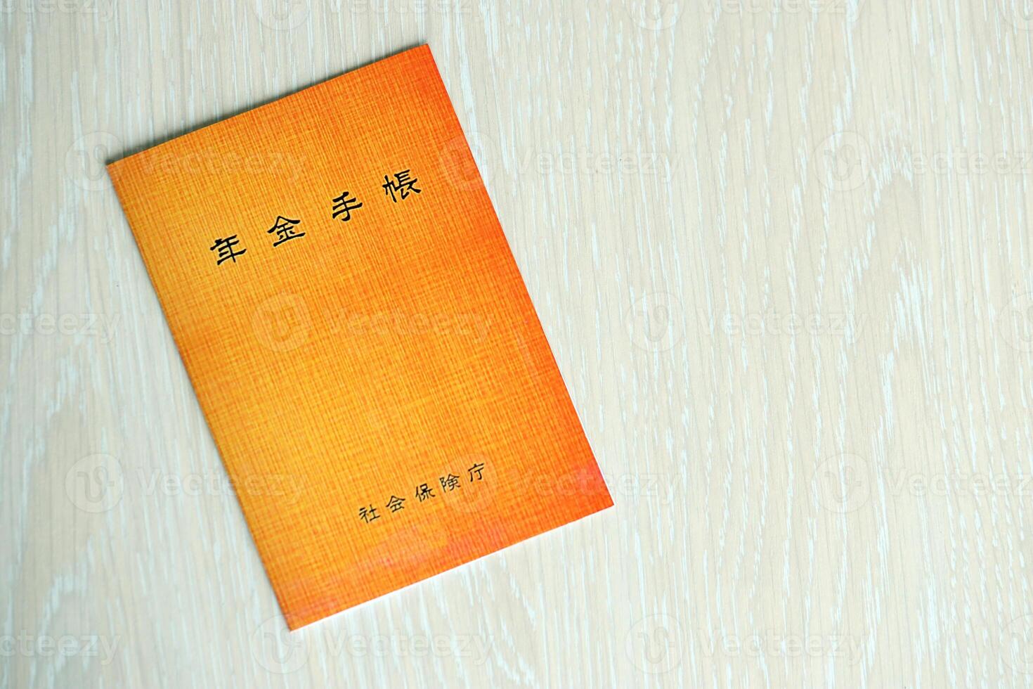 Japanese pension insurance booklet on table. Orange pension book for japan pensioners photo