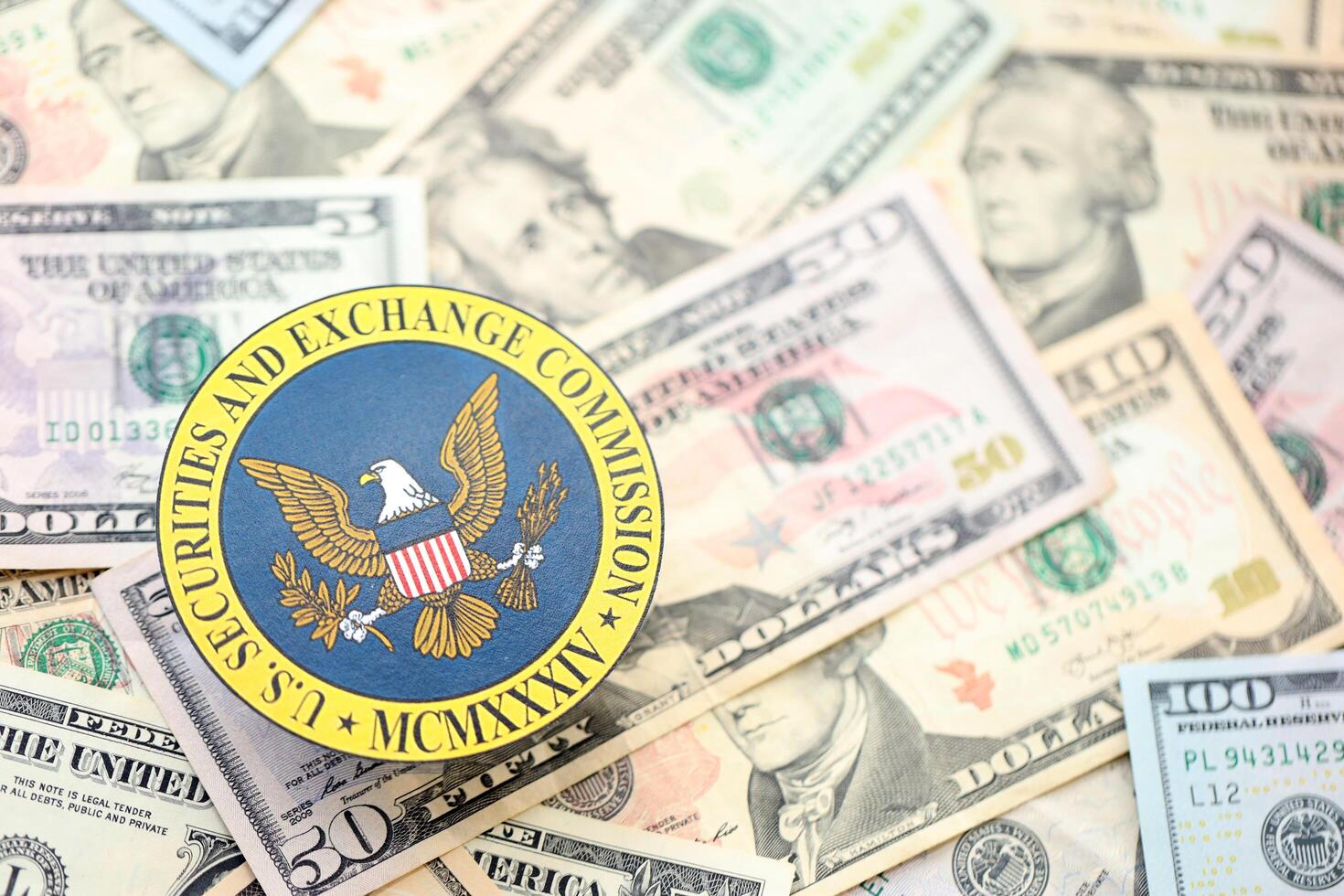KYIV, UKRAINE - JUNE 26, 2024 U.S. Securities and Exchange Commission coat of arms on big amount of US dollar banknotes photo