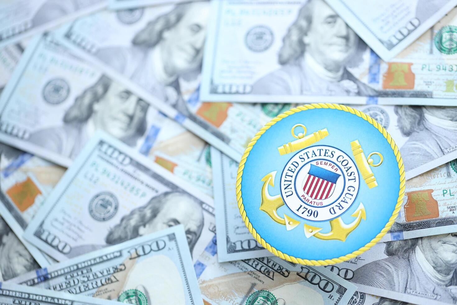 KYIV, UKRAINE - JUNE 26, 2024 United States Coast Guard coat of arms on big amount of US dollar banknotes photo