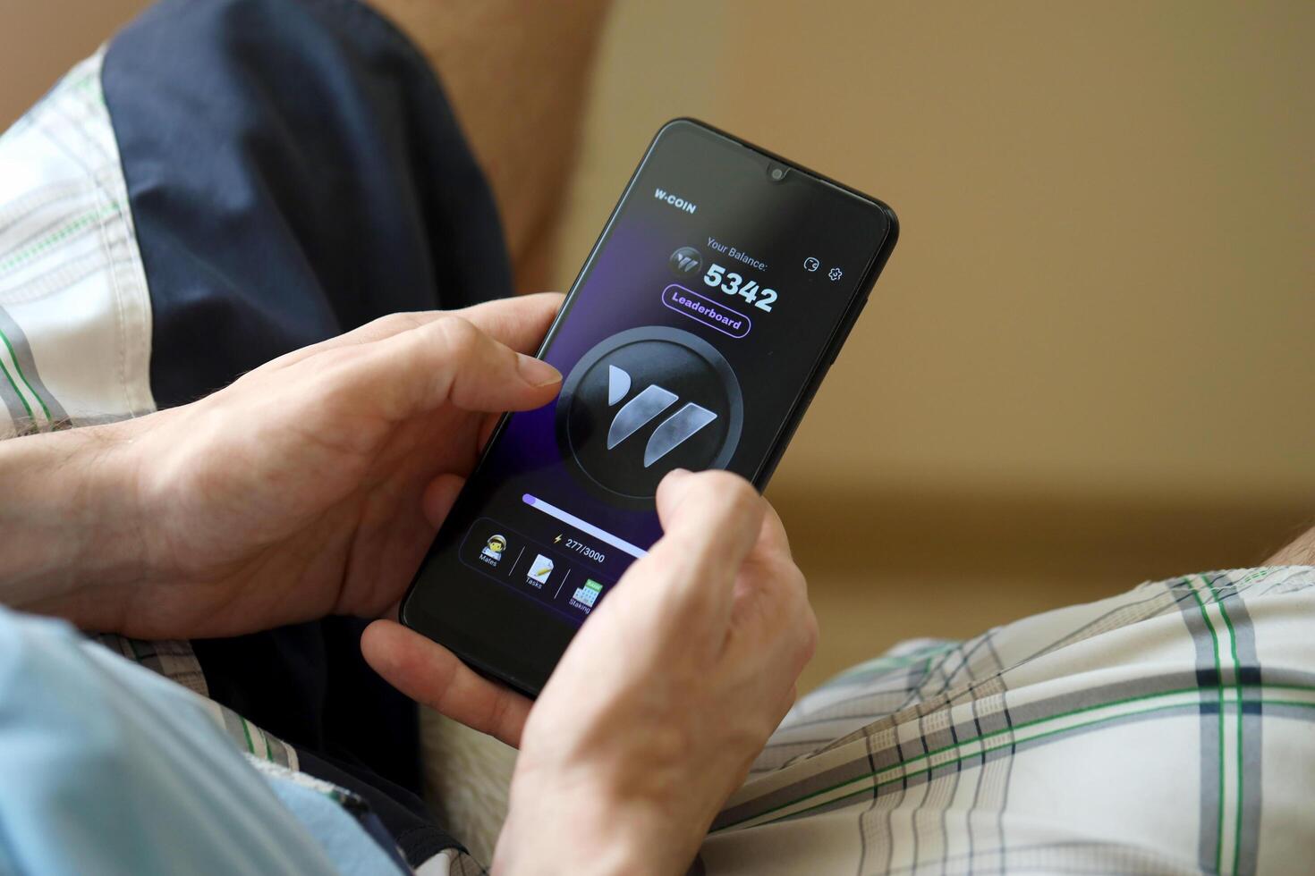 KYIV, UKRAINE - APRIL 20, 2024 W-coin telegram bot on smartphone screen. W-coin is a viral Telegram based crypto game for earn tokens by managing virtual crypto exchange photo