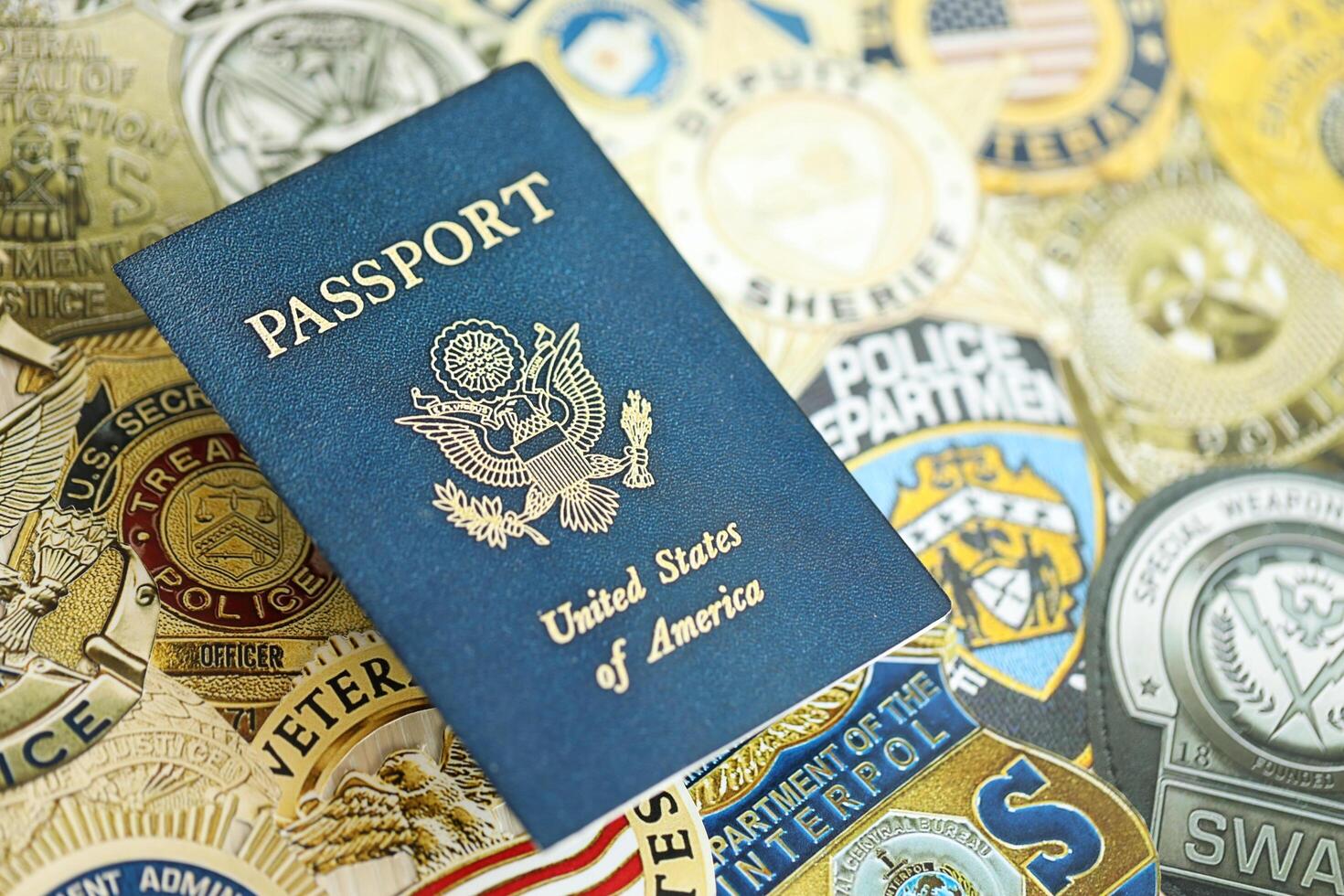 KYIV, UKRAINE - MARCH 9, 2024 US Passport lies on badges of different United States police departments printed on paper photo