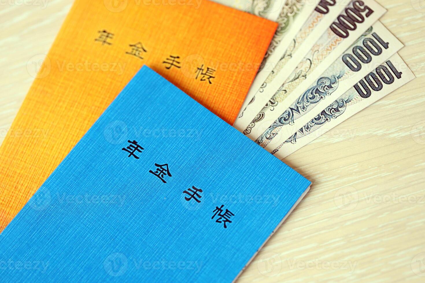 Japanese pension insurance booklets on table with yen money bills. Blue and orange books photo