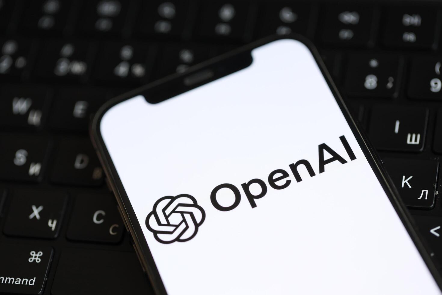 KYIV, UKRAINE - MARCH 17, 2024 OpenAI logo on iPhone display screen and MacBook keyboard photo